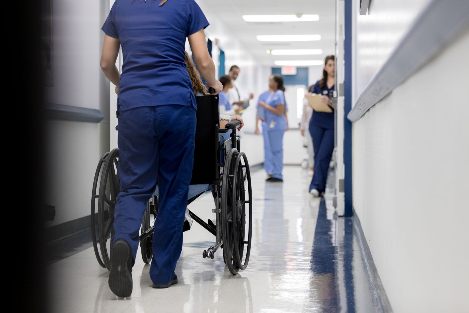 Nurse pushing a patient in a wheelchair at a hospital image